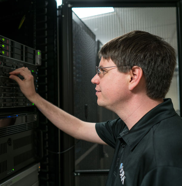 Photo of a person using their right hand to work on a computer server.