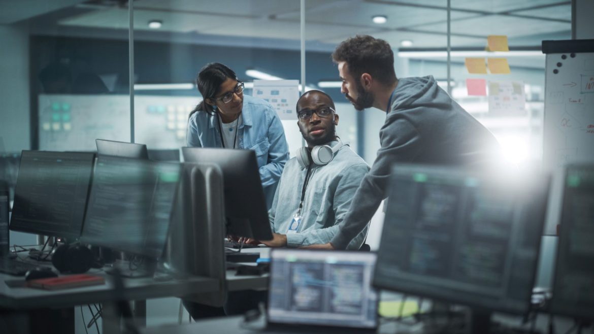 three IT specialists working on a project together in an office